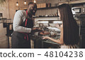 Male barista helps a girl to choose a dessert 48104238