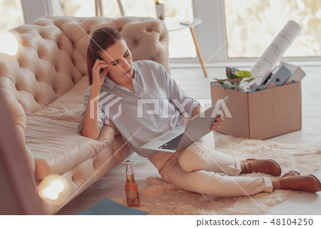 Busy young woman being attentive while working with a laptop Busy young woman being attentive while working with a laptop 48104250