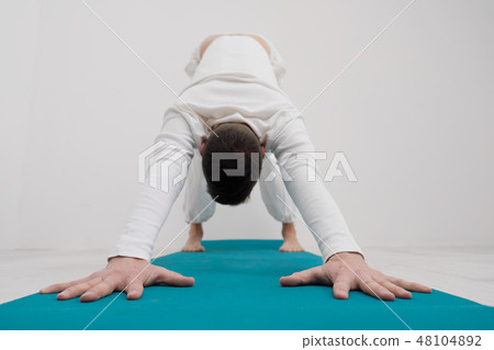 Handsome man doing yoga exercises isolated on a white background Handsome man doing yoga exercises isolated on a white background 48104892