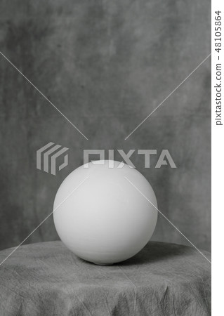 Plaster white sphere or ball, on a gray fabric artistic background. 48105864