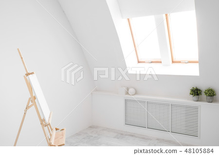White and bright studio with a window. Workspace of the artist. Easel, canvases and plaster figures 48105884