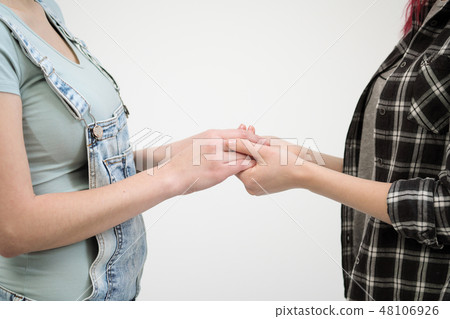 Two girls in jeans hold hands close up. White background. Homosexual lesbian couple. 48106926