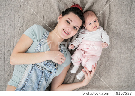 Happy smiling mother and baby lying on bed at home, top view 48107558
