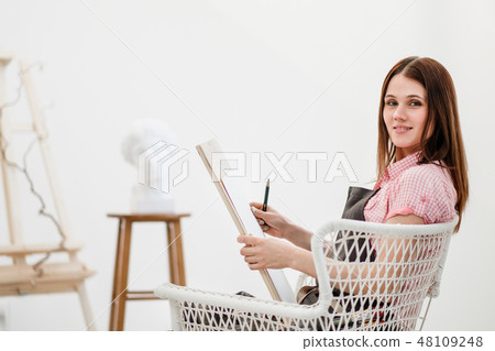 Young woman artist draws a pencil on canvas. 48109248