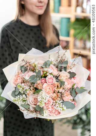 beautiful fresh cut bouquet of mixed flowers in woman hand. the work of the florist at a flower shop beautiful fresh cut bouquet of mixed flowers in woman hand. the work of the florist at a flower shop 48109563