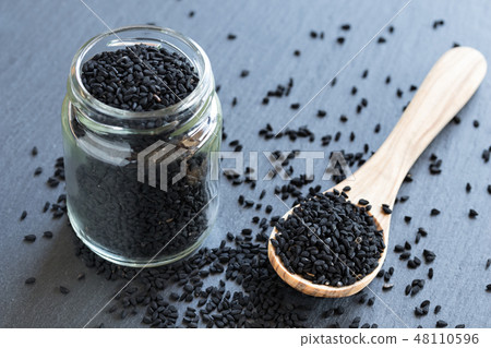 Black cumin seeds on a spoon and in a jar Black cumin seeds on a spoon and in a jar 48110596