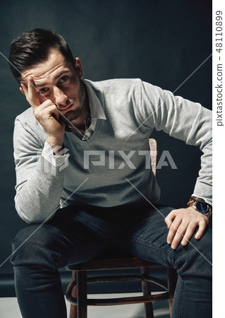 Thoughtful young man posing on dark background Thoughtful young man posing on dark background 48110899