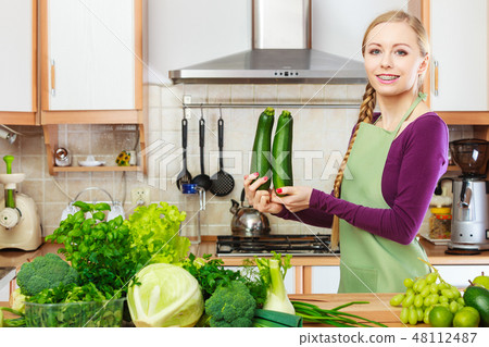 Woman housewife in kitchen with green vegetables Woman housewife in kitchen with green vegetables 48112487