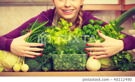 Smiling woman in kitchen with green vegetables 48112490