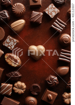 A heart-shaped chocolate taken from a bird's-eye view with a red-brown background A heart-shaped chocolate taken from a bird's-eye view with a red-brown background 48112887