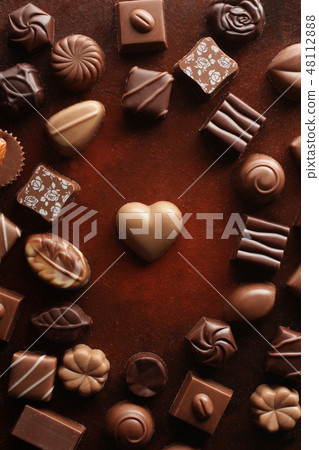 A heart-shaped chocolate taken from a bird's-eye view with a red-brown background A heart-shaped chocolate taken from a bird's-eye view with a red-brown background 48112888