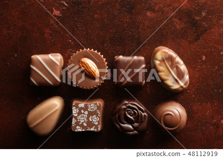 A heart-shaped chocolate taken from a bird's-eye view with a red-brown background 48112919