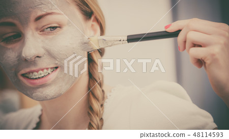 Woman applying with brush clay mud mask to her face 48114593