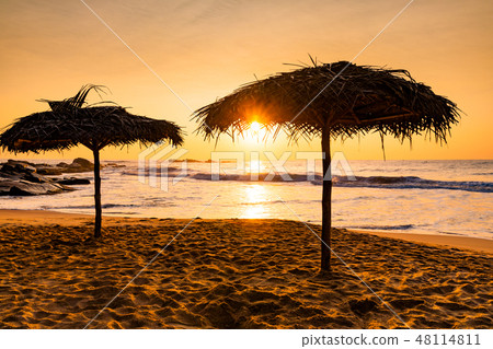 Two beach umbrellas at sunrise on a sandy beach. Tropical island. 48114811