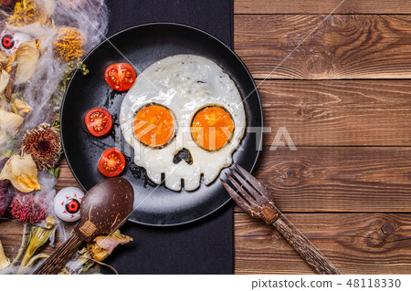 Fried eggs in the shape of a skull and fresh tomatoes. Breakfast in Halloween decorations. 48118330