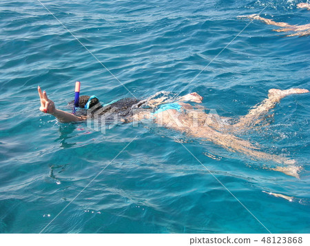 Beautiful woman swims in the Red Sea and engaged in snorkelling with a snorkel and mask. And she Beautiful woman swims in the Red Sea and engaged in snorkelling with a snorkel and mask. And she 48123868
