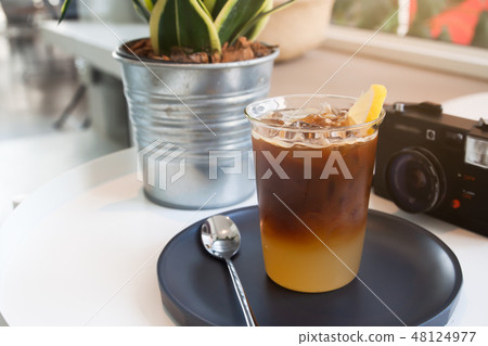 Glass of coffee and camera on the table in cafe. 48124977
