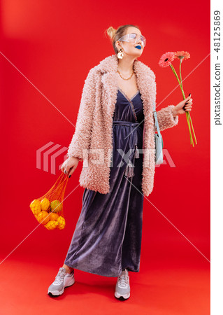 Fashionable woman coming home with bag of fruits and flowers Fashionable woman coming home with bag of fruits and flowers 48125869