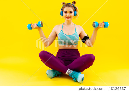 Woman wearing colorful sport clothes holding hand weights 48126887