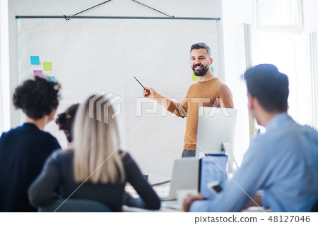 A businessman giving a presentation to colleagues in a modern office. A businessman giving a presentation to colleagues in a modern office. 48127046