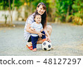 Mother practices child to play a soccer football 48127297