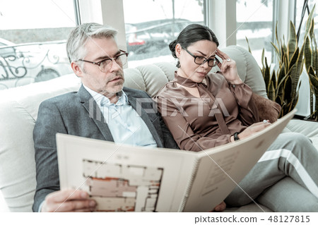 Brunette adult businesswoman in a brown satin blouse looking thoughtful Brunette adult businesswoman in a brown satin blouse looking thoughtful 48127815