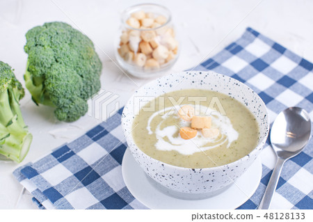 Cream soup puree with broccoli, cream and crackers. Lunch of vegetables on a light background. Plate Cream soup puree with broccoli, cream and crackers. Lunch of vegetables on a light background. Plate 48128133