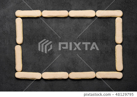 Frame made of Italian Savoiardi ladyfingers Biscuits on dark concrete backgound Frame made of Italian Savoiardi ladyfingers Biscuits on dark concrete backgound 48129795