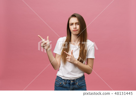 Closeup of serious strict young woman wears white shirt looks stressed and pointing up with finger Closeup of serious strict young woman wears white shirt looks stressed and pointing up with finger 48131445
