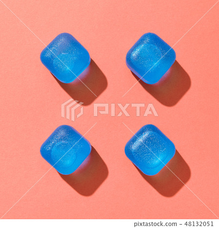 Four blue ice cubes with shadows on a background in a trend color of the year 2019 Living Coral 48132051