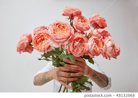 Young girl's hands is holding a bouquet of fresh flowers in her hands with tatoo in a color of the Young girl's hands is holding a bouquet of fresh flowers in her hands with tatoo in a color of the 48132068