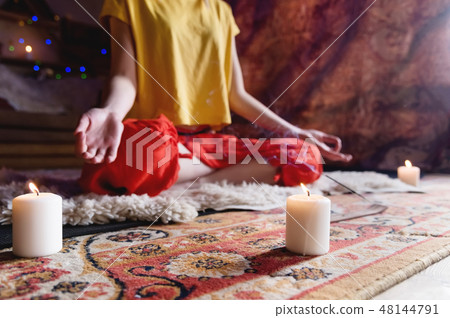 Close-up of woman's hand in yoga lotus pose meditating in a crafting room with candles Close-up of woman's hand in yoga lotus pose meditating in a crafting room with candles 48144791