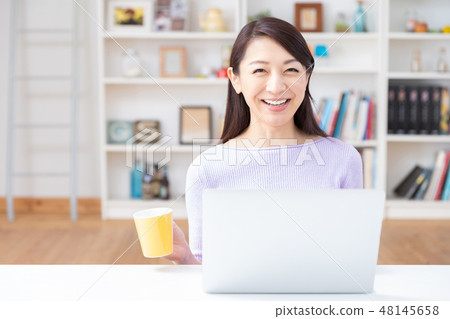 觀看一台便攜式計算機的婦女在屋子裡 觀看一台便攜式計算機的婦女在屋子裡 48145658