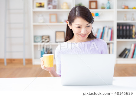 觀看一台便攜式計算機的婦女在屋子裡 觀看一台便攜式計算機的婦女在屋子裡 48145659