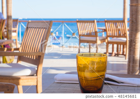 Empty orange glass on table at beach cafe 48145681