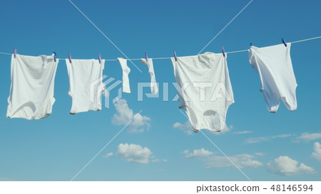 White linen dries on a rope against a clean blue sky White linen dries on a rope against a clean blue sky 48146594