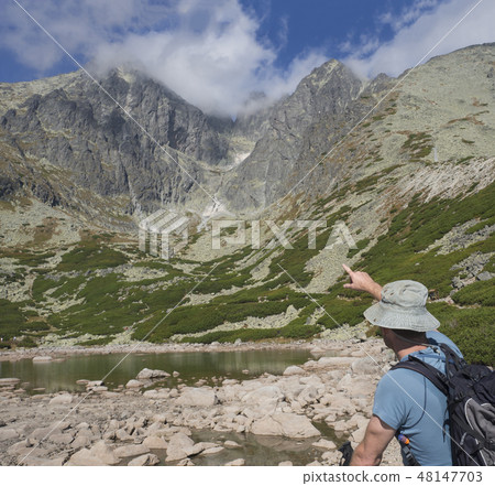 Young man hiker looking and point to mountain Peak Lomnicky stit 2 634 m at Summer, the highest Young man hiker looking and point to mountain Peak Lomnicky stit 2 634 m at Summer, the highest 48147703