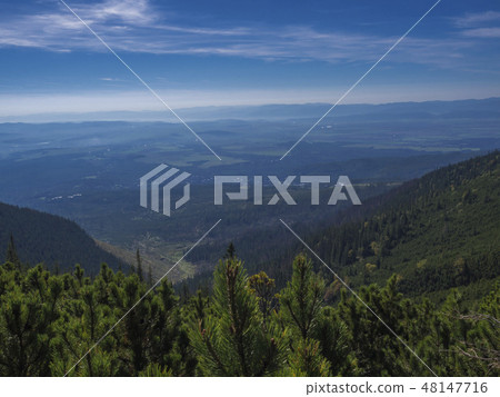 View from tatra mountains trail on valley with Tatranska lomnice and blue misty slopes of hills in View from tatra mountains trail on valley with Tatranska lomnice and blue misty slopes of hills in 48147716