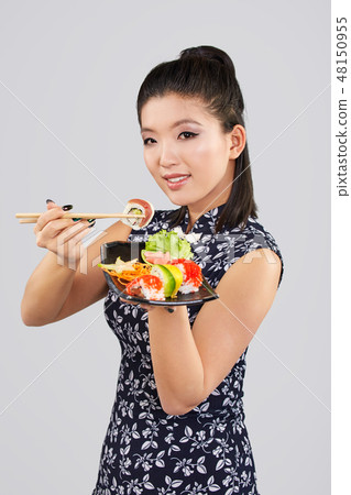 Young beautiful asian woman eating sushi with chopsticks, Young beautiful asian woman eating sushi with chopsticks, 48150955