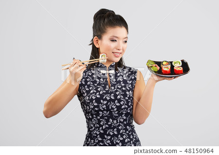Young beautiful asian woman eating sushi with chopsticks, Young beautiful asian woman eating sushi with chopsticks, 48150964