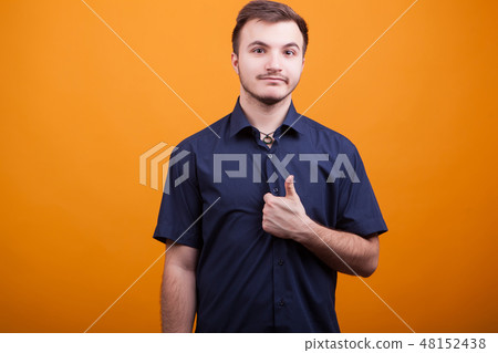 Handsome young man showing thumb up on yellow background Handsome young man showing thumb up on yellow background 48152438