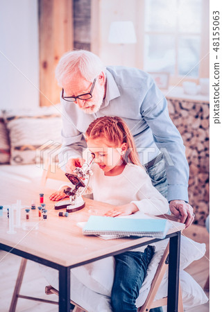 Old man helping kid watching in microscope Old man helping kid watching in microscope 48155063