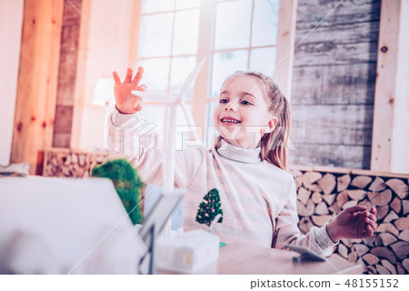 Cheerful young lady touching toy small windmill Cheerful young lady touching toy small windmill 48155152