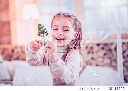 Young lady viewing her plaything sitting at table Young lady viewing her plaything sitting at table 48155252