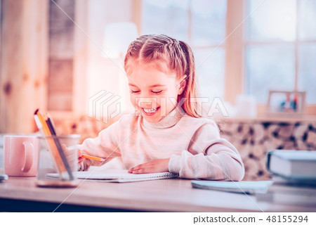 Adorable young schoolgirl smiling while drawing in her album Adorable young schoolgirl smiling while drawing in her album 48155294