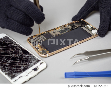 Technician repairing broken smartphone on desk Technician repairing broken smartphone on desk 48155968