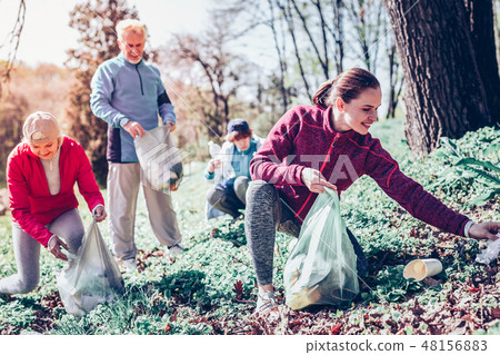 Beautiful dark-haired woman gathering plastic in forest 48156883
