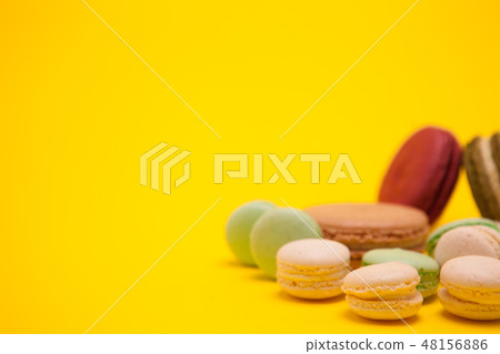 Little butter cream macaroons flavors next to different macarons on yellow background 48156886