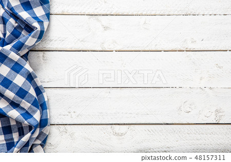 Blue checkered kitchen tablecloth on wooden table. 48157311