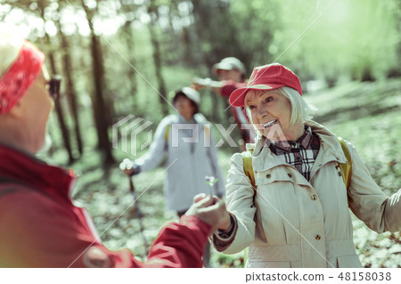 Smiling elderly woman walking in the forest with her partner Smiling elderly woman walking in the forest with her partner 48158038